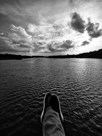 Low section of person in sea against sky