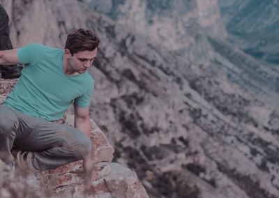 High angle view of man crouching on cliff