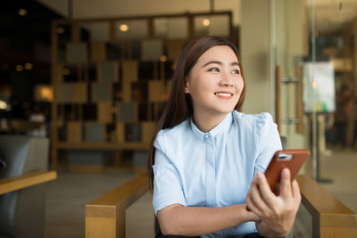 Portrait of smiling young woman using smart phone