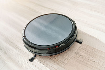 From above of round robotic vacuum cleaner sliding on light laminate floor