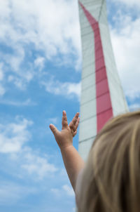 Cropped image of girl reaching tower against sky