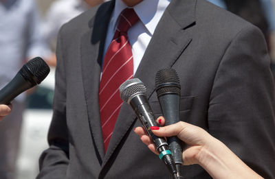 Cropped hands of people holding microphone by businessman