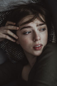 Worried woman looking away while lying on sofa