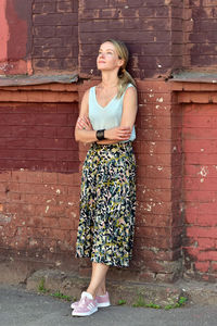 Full length of woman standing against brick wall