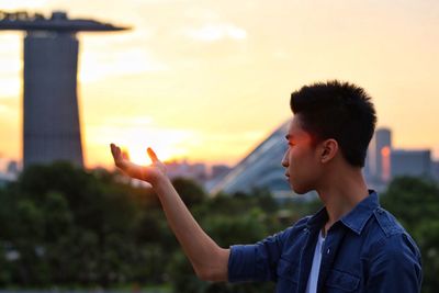 Optical illusion of young man holding sun at marina barrage