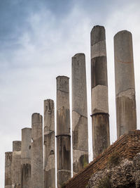 Low angle view of broken columns against sky
