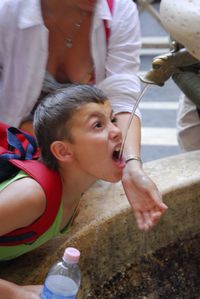 Mother with son drinking water from fountain