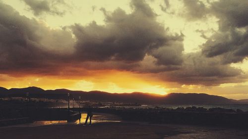 Scenic view of sea against cloudy sky at sunset