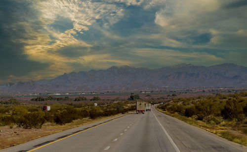 Road leading towards mountains against sky