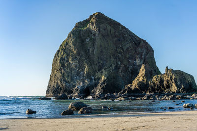 Rock formation on beach against clear blue sky