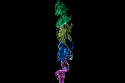 Close-up of multi colored illuminated smoke against black background