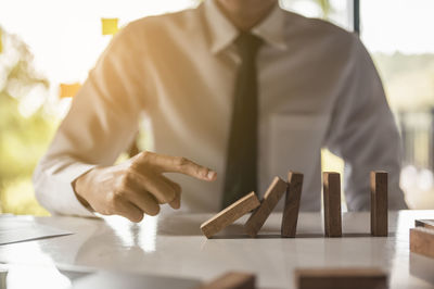 Midsection of businessman pushing dominoes on table