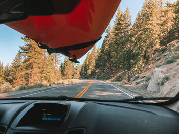 Road amidst trees seen through car windshield