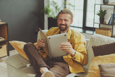 Young woman using laptop while sitting on sofa at home