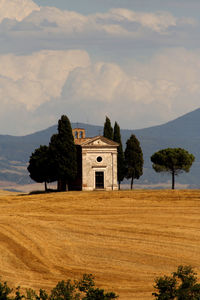 Built structure on field by trees against sky