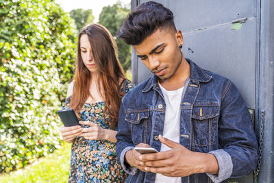 Couple using smart phone while standing outdoors