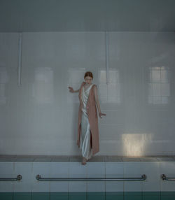 Full length of teenage girl standing by swimming pool