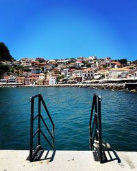 View of townscape by sea against clear blue sky