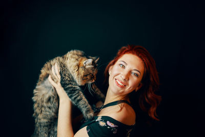 Portrait of smiling young woman against black background