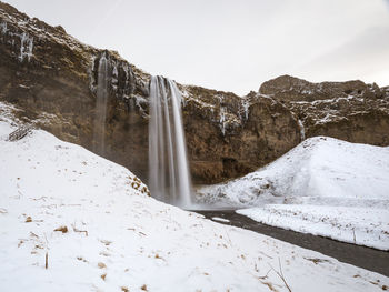 Scenic view of sejlandsfoss waterfall covered by snow, in iceland, at winter