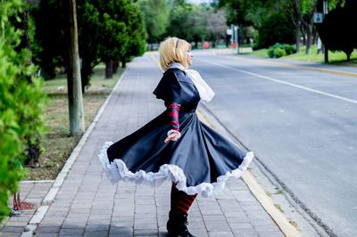 Rear view of woman standing on footpath