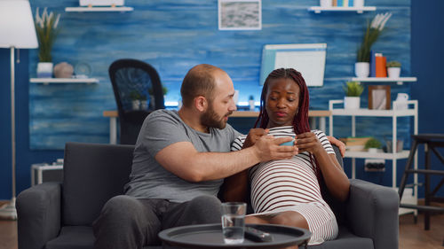 Man sitting with pregnant woman sitting on sofa at home