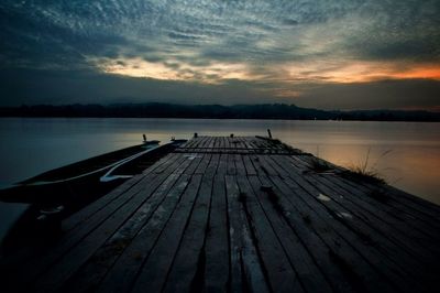 Wooden pier on lake against cloudy sky