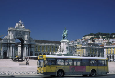 Bus on street by king jose i statue against rua augusta arch at praca do comercio