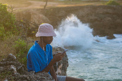 Side view of woman sitting on rock