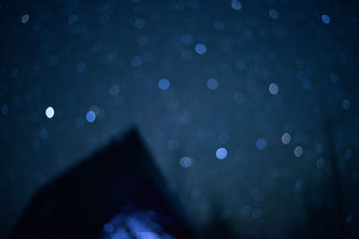 Defocused image of hand on wet illuminated city at night