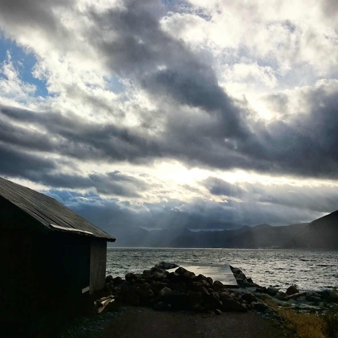 sky, cloud - sky, built structure, architecture, building exterior, cloudy, water, weather, house, sea, cloud, scenics, beauty in nature, tranquility, nature, tranquil scene, overcast, outdoors, horizon over water, roof