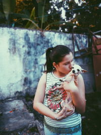 Girl kissing chihuahua dog in back yard