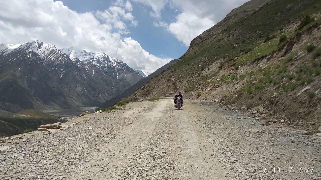 REAR VIEW OF WOMAN WALKING ON ROAD AGAINST MOUNTAIN