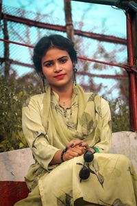 Portrait of young woman sitting on railing