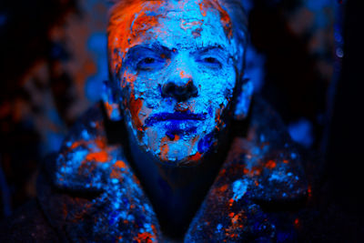 Close-up portrait of man covered with powder paint against black background