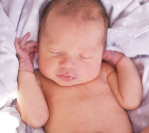 Close-up of newborn baby girl sleeping on bed