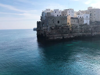 Sea by buildings against sky