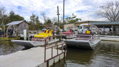 Boats moored at harbor against sky