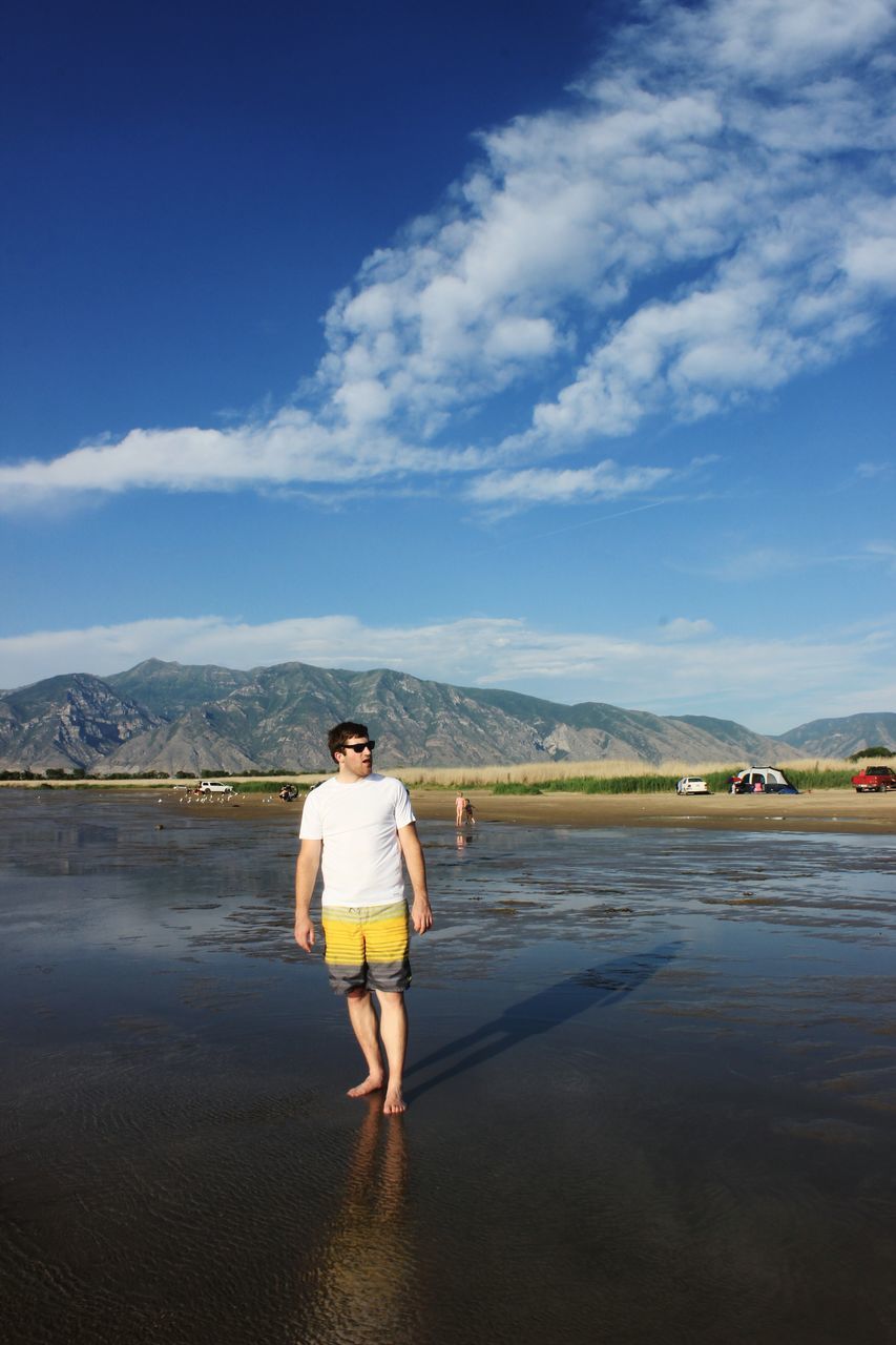 sky, rear view, full length, lifestyles, leisure activity, mountain, standing, casual clothing, water, cloud - sky, walking, cloud, person, nature, mountain range, scenics, men, day