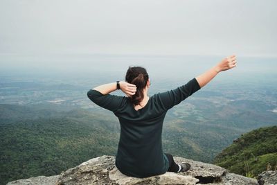 Woman on rock looking at mountains against sky