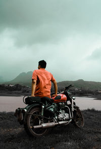 Rear view of man sitting on bike mountain against sky