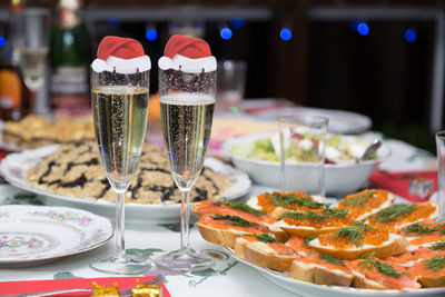 Close-up of champagne flutes with santa hats on table