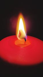 Close-up of lit candle against black background