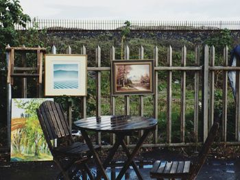 Empty chairs and table on field against sky