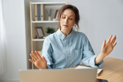 Portrait of young woman using laptop at home