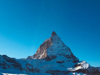 Scenic view of snowcapped mountains against clear blue sky