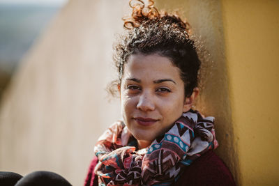 Portrait of smiling woman sitting against wall