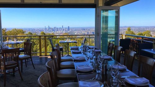 Empty chairs and tables in restaurant against clear sky