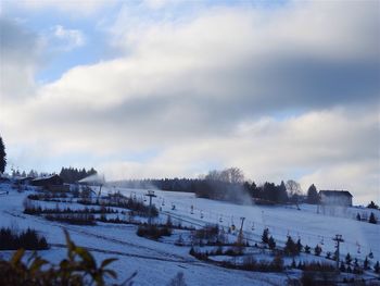 View of snow covered landscape against cloudy sky