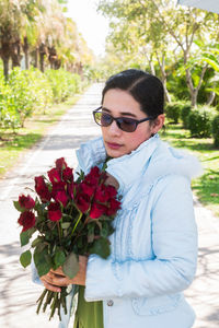 Young woman wearing sunglasses standing against wall